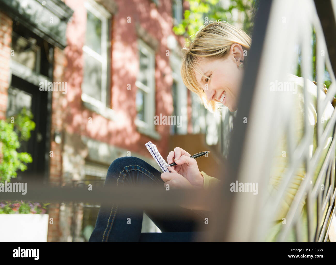 USA, New York, Williamsburg, Brooklyn, Smiling woman writing diary Stock Photo