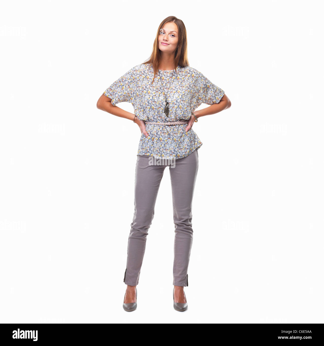 Beautiful smiling woman standing with hands on hips against white ...