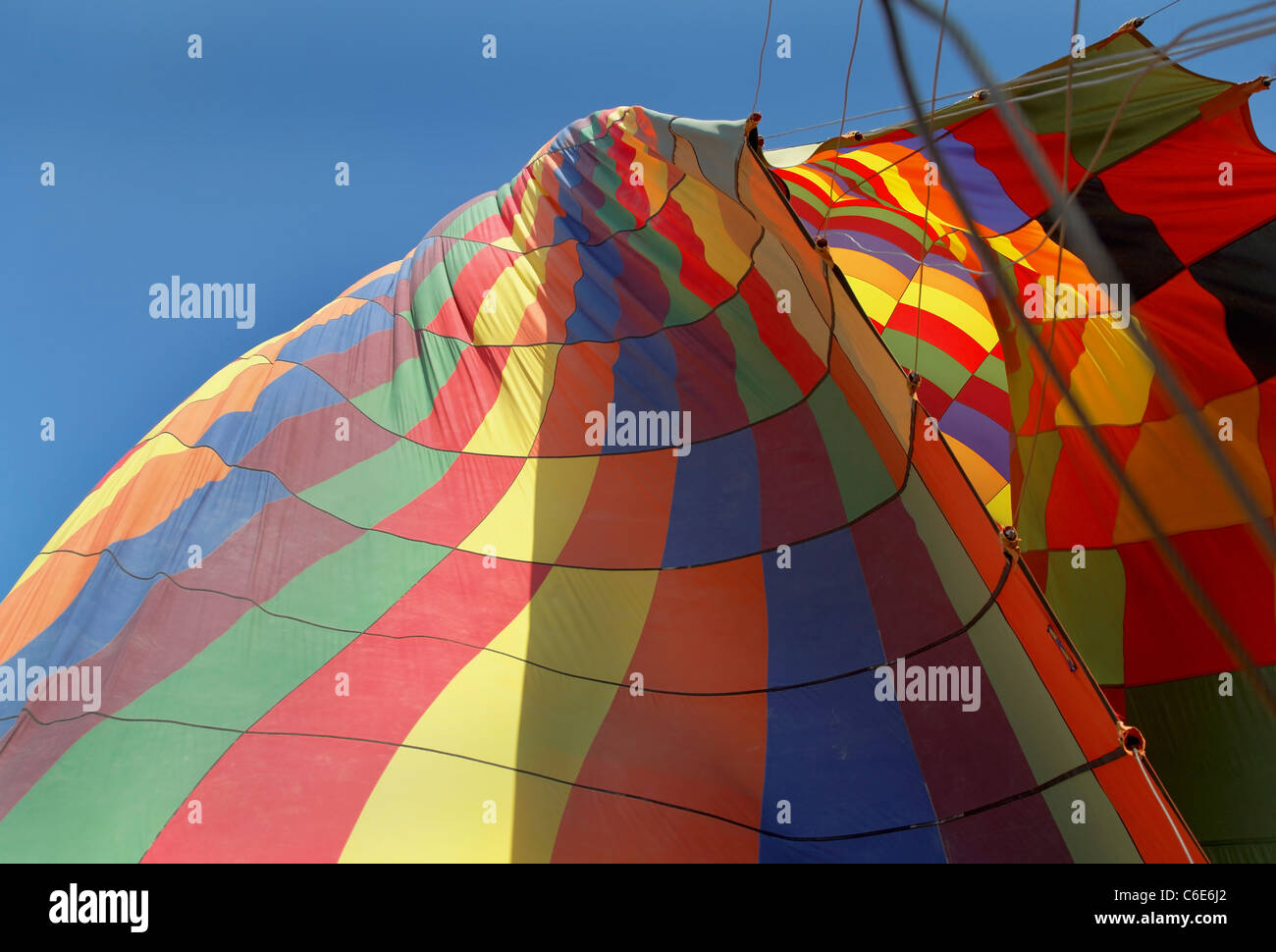 Landscape of deflating hot air balloon, multi colored, blue sky, guy ropes, guide ropes, crop space and copy space Stock Photo