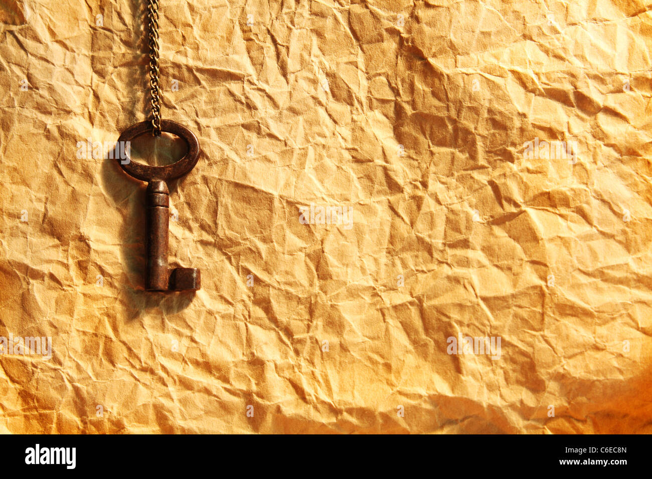 Blank sheet of crumpled paper and old key on chain Stock Photo