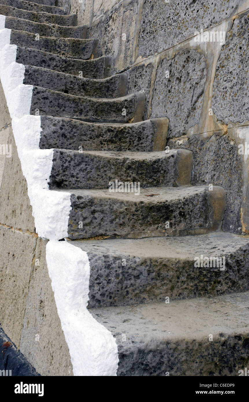 Worn stone steps linking the lower and upper levels of The Cobb, the main harbour wall at Lyme Regis, Dorset, England Stock Photo