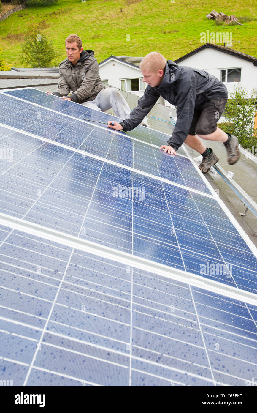 Technicians fitting solar photo voltaic panels to a house roof in Ambleside, Cumbria, UK. Stock Photo