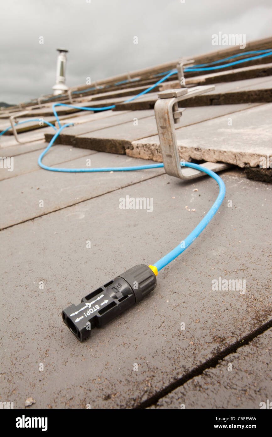 Fitting wiring to a house roof in Ambleside, Cumbria, UK, to support solar photo voltaic panels. Stock Photo