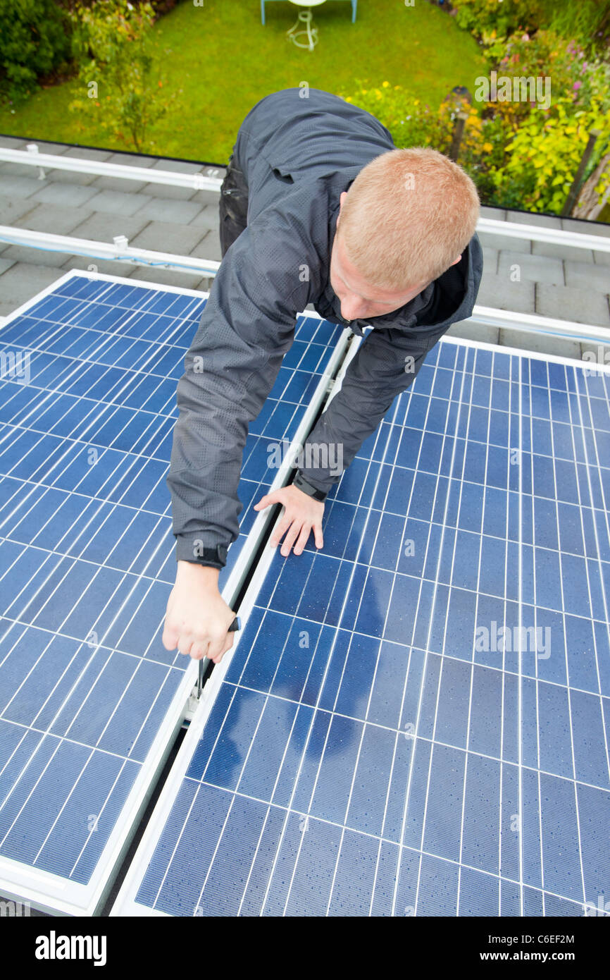 Technicians fitting solar photo voltaic panels to a house roof in Ambleside, Cumbria, UK. Stock Photo