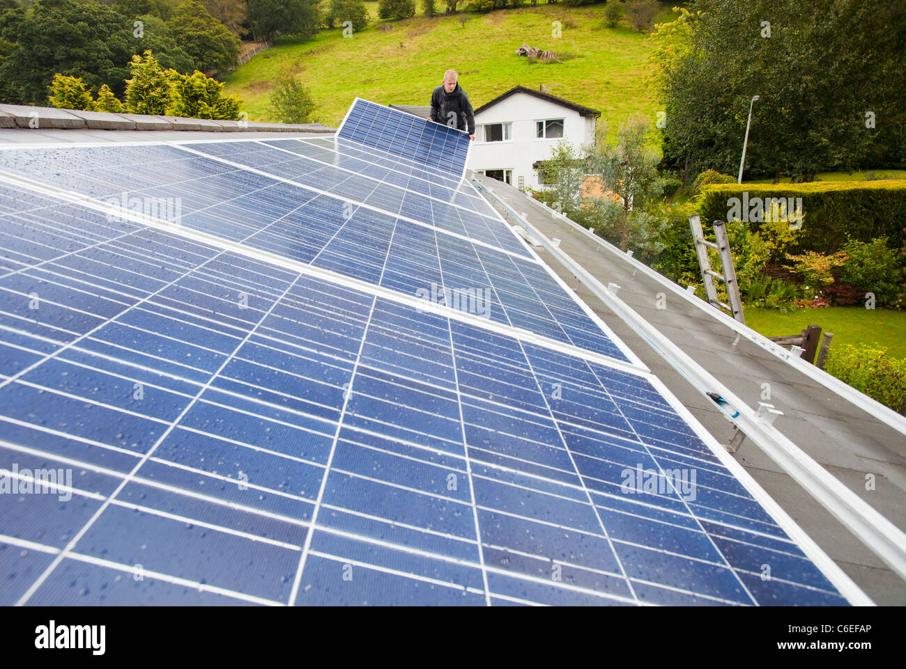 Technicians fitting solar photo voltaic panels to a house roof in Ambleside, Cumbria, UK. Stock Photo