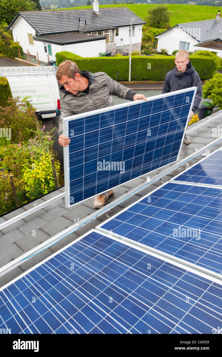 Technicians fitting solar photo voltaic panels to a house roof in Ambleside, Cumbria, UK. Stock Photo