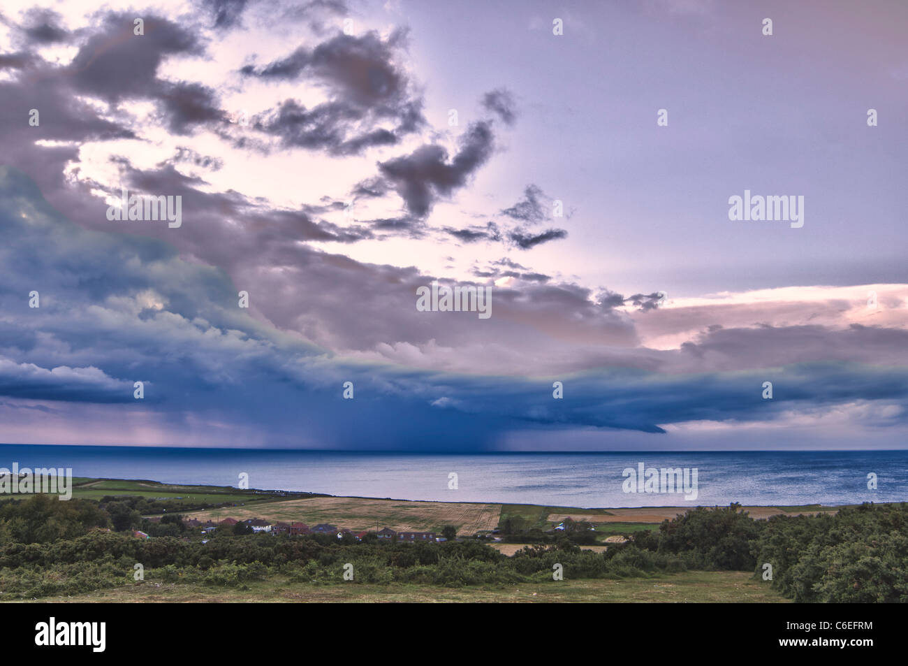 Looking our from Incleborough Hill, Norfolk, over West Runton to storm at sea, dusk. Stock Photo