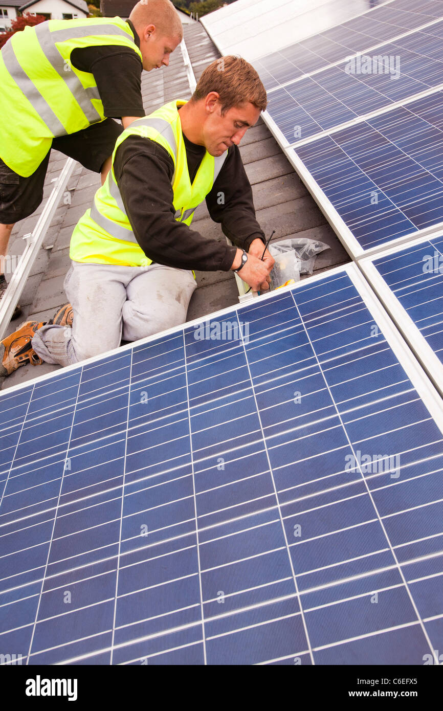 Technicians fitting solar photo voltaic panels to a house roof in Ambleside, Cumbria, UK. Stock Photo