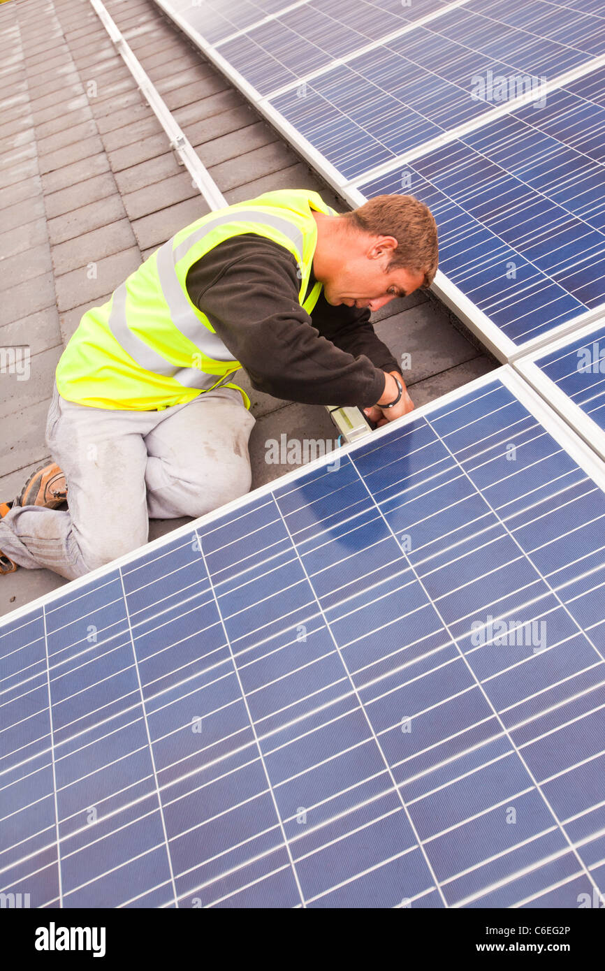 Technicians fitting solar photo voltaic panels to a house roof in Ambleside, Cumbria, UK. Stock Photo