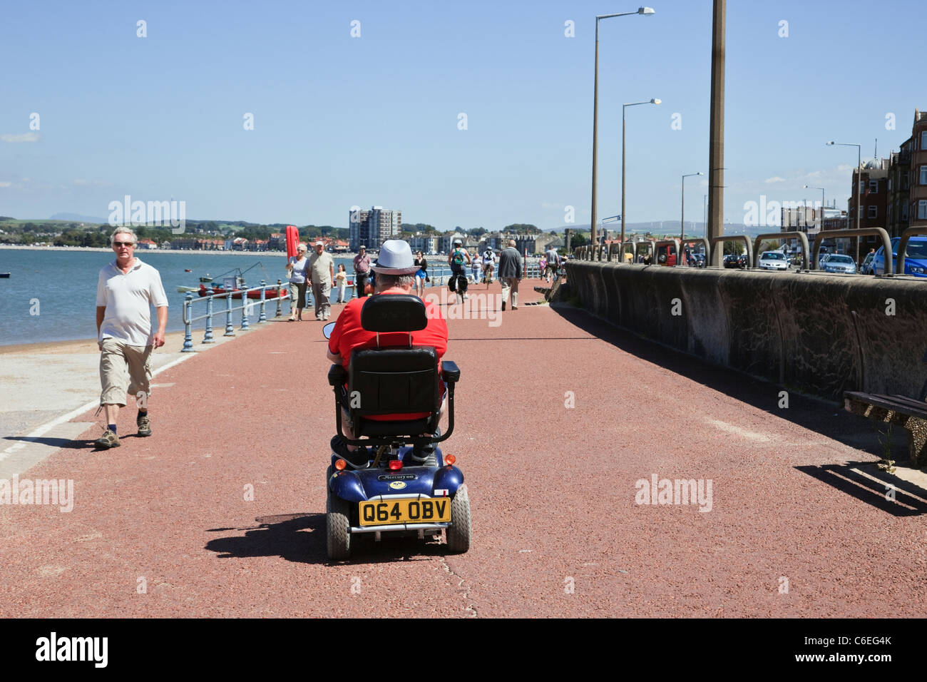 Senior man using a mobility scooter on the seafront promenade. Morecambe, Lancashire, England, UK, Britain Stock Photo
