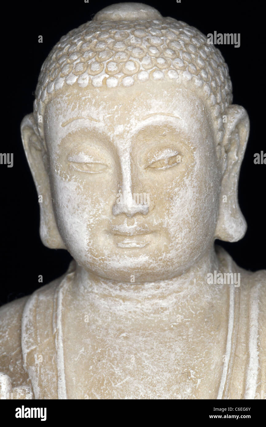 Statue of Buddha meditating on lotus flower against black background Stock Photo