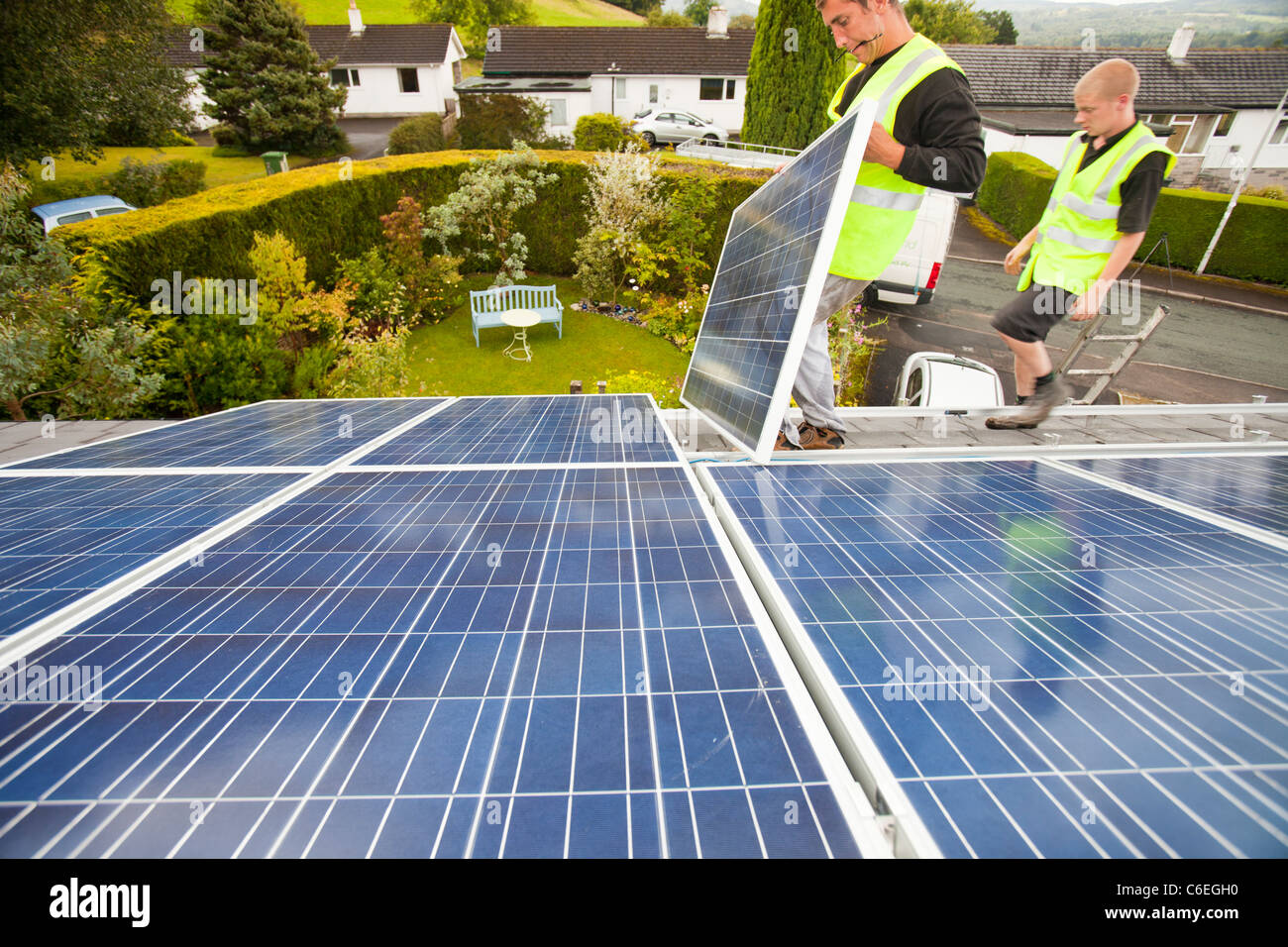 Technicians fitting solar photo voltaic panels to a house roof in Ambleside, Cumbria, UK. Stock Photo