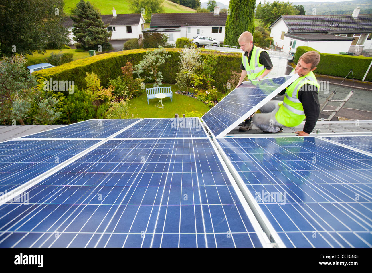Technicians fitting solar photo voltaic panels to a house roof in Ambleside, Cumbria, UK Stock