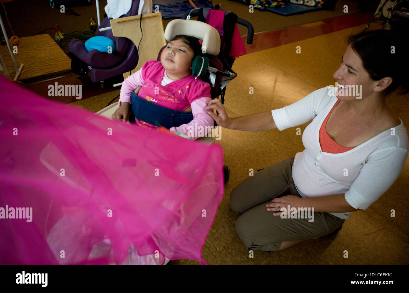 Speech Therapist works with deaf blind child on association between hitting switch with her head, and a fan blowing/moving cloth Stock Photo