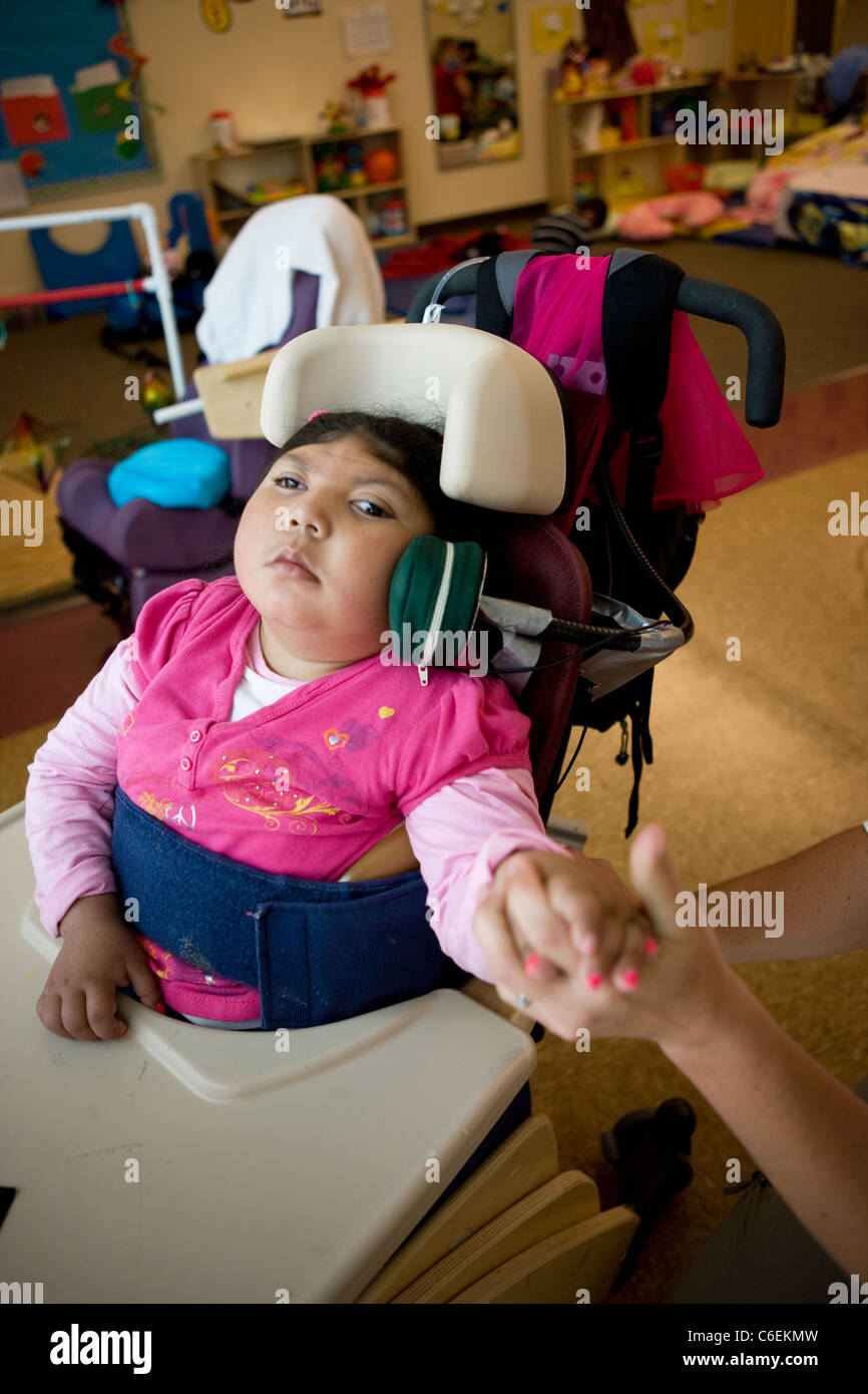 Female deaf blind student works with speech therapist on using a head switch to turn on a fan, make choices, in her school. Stock Photo