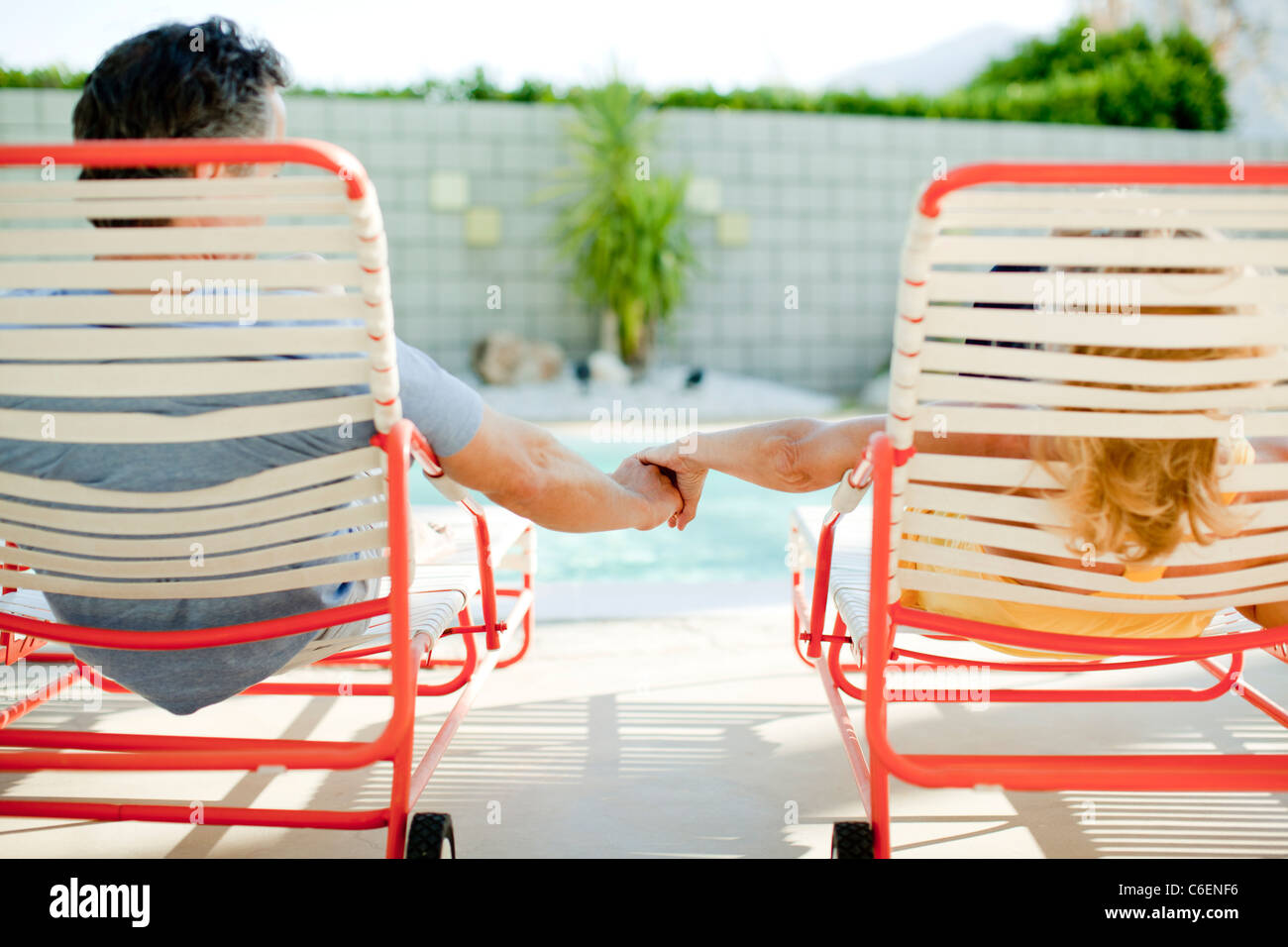 Couple holding hands in lounge chair near swimming pool Stock Photo Alamy