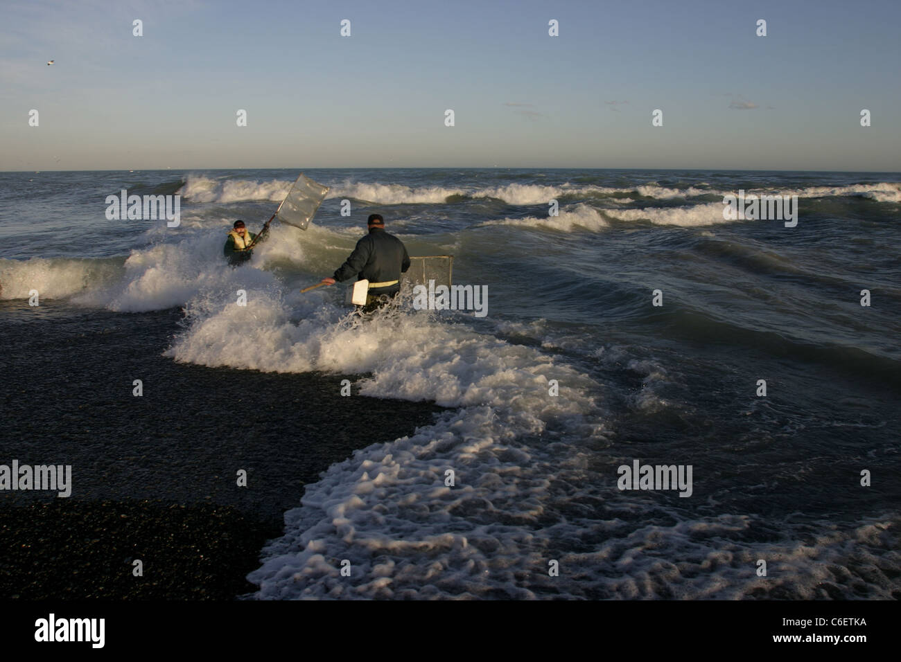 Whitebait fishermen waist high in breaking waves at the mouth of the Rakaia river. Stock Photo
