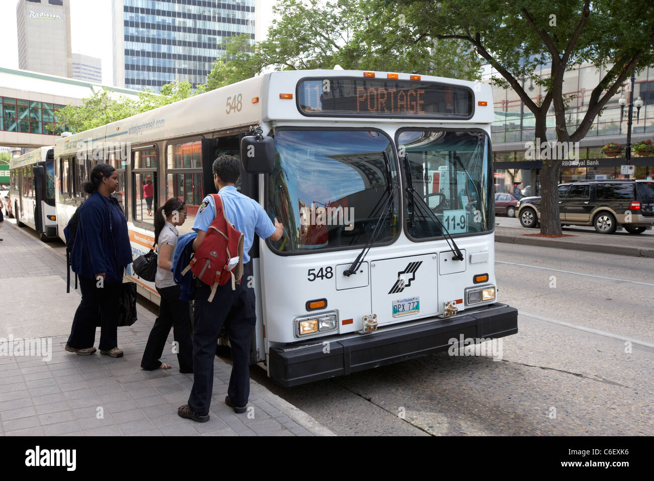 passengers boarding winnipeg transit bus at bus stop on portage ave