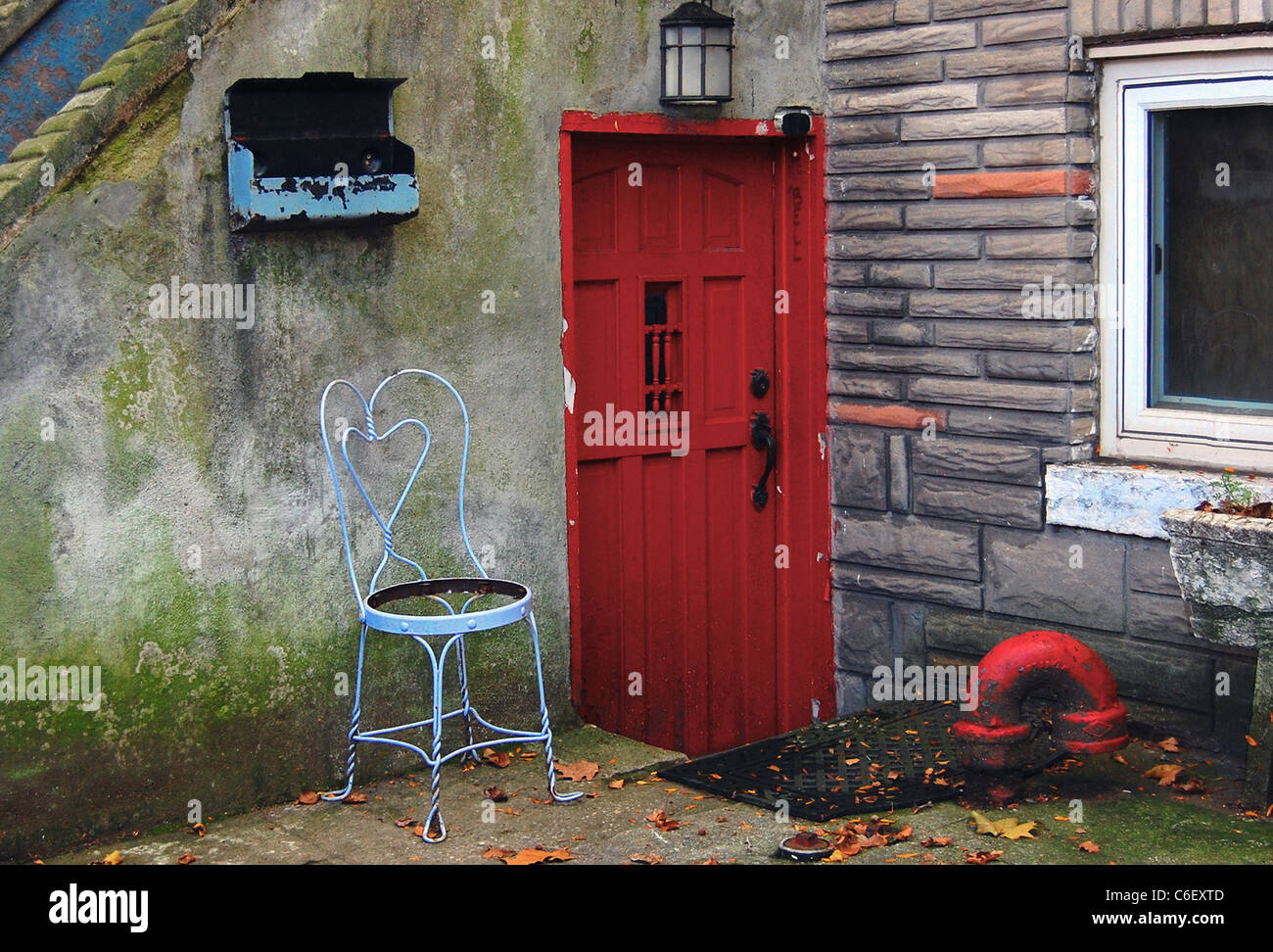 Basement apartment with red door and antique wire garden chair Stock Photo
