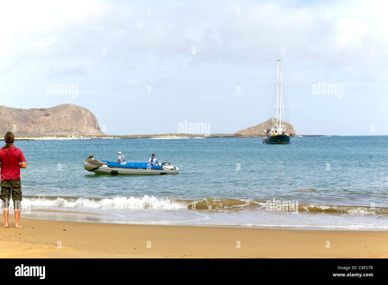 Tourist waits on beach for panga to take him back to the yacht, Punta Pitt, San Christobel, Galapagos Stock Photo