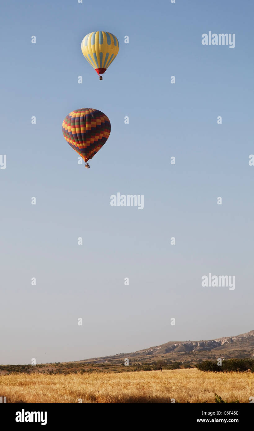 hot air balloons sailing in blue sky low level flight over wilderness and flat terrain, portrait, copy space and crop area Stock Photo