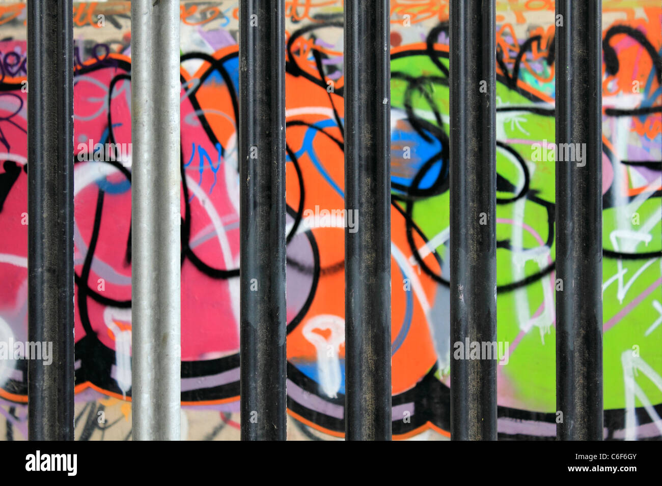 Graffiti behind bars on walls under the A316 flyover Hanworth, Surrey, England, UK Stock Photo