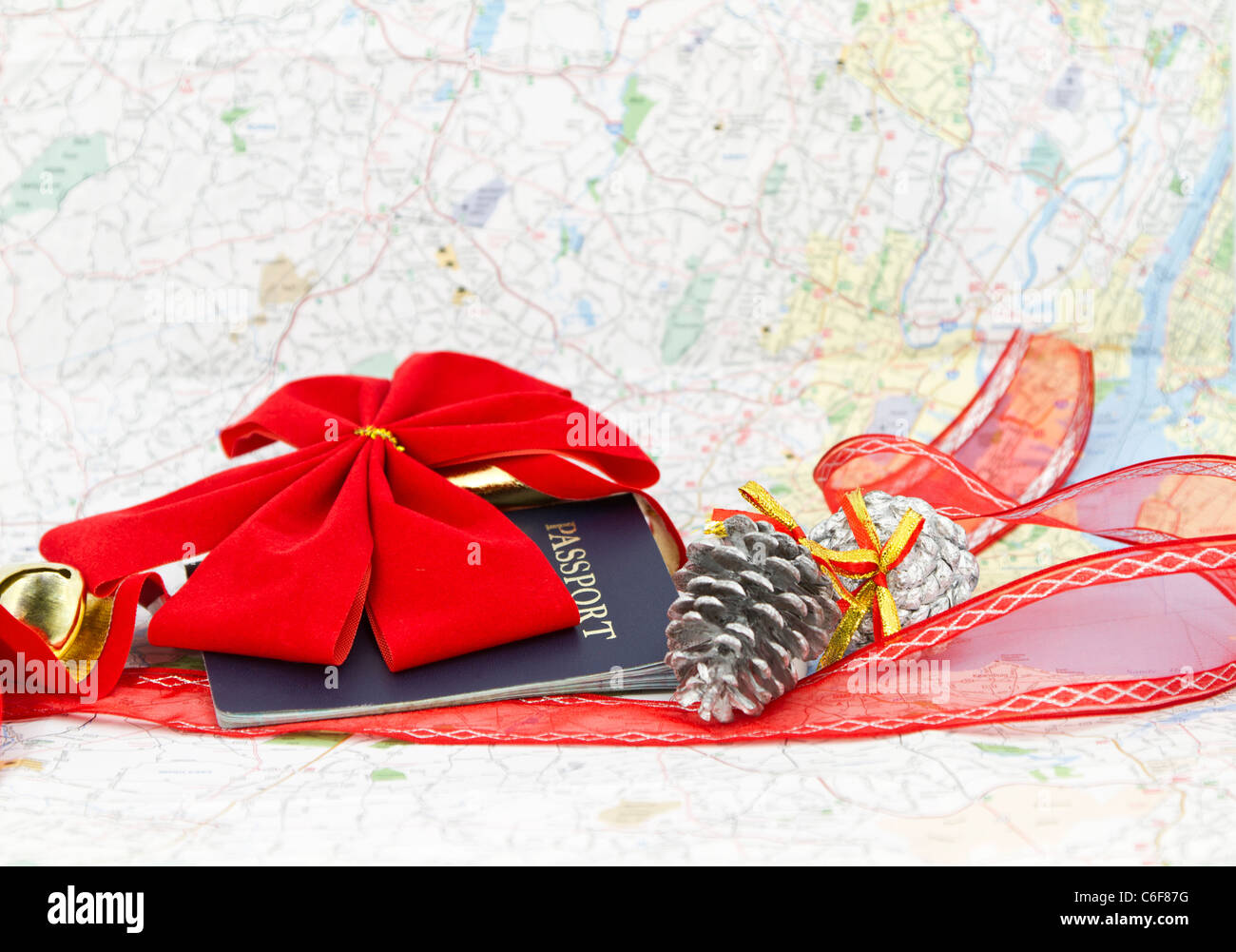 Passport placed with red holiday bow, ribbon, and gold bell with map background; copy space in map area. Stock Photo
