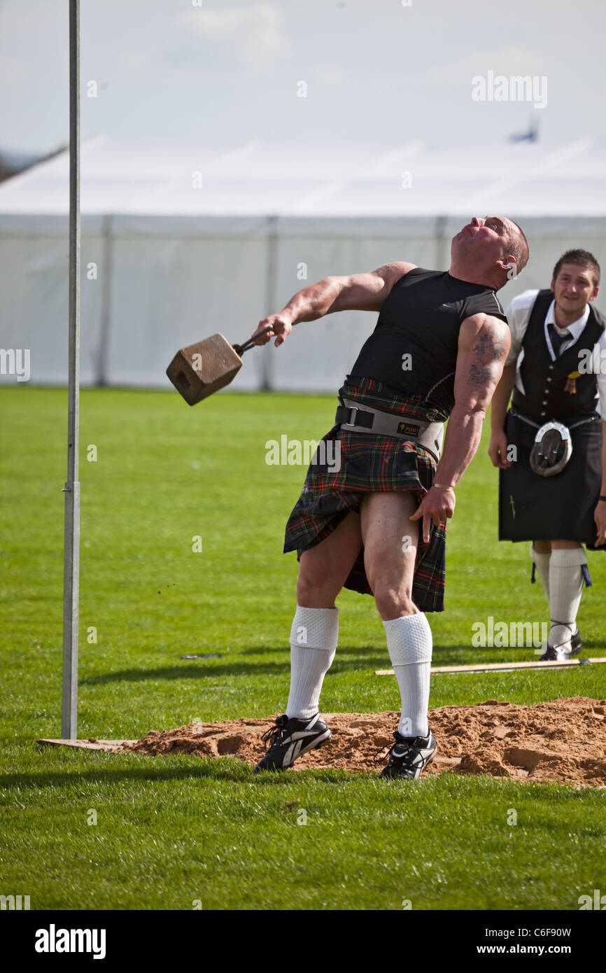 Heavy athlete throwing a 56lb weight for height over a bar while