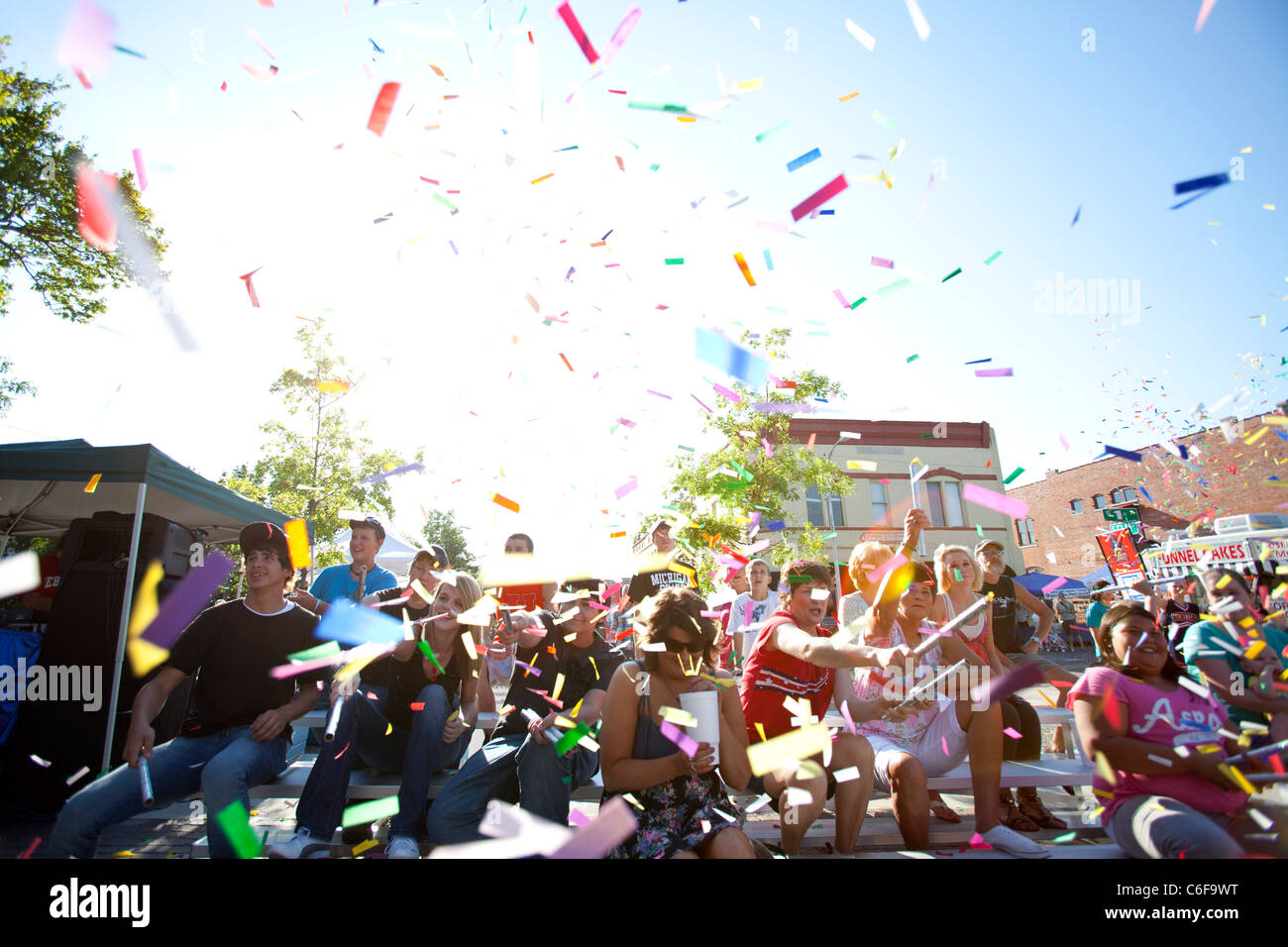 A group of people launch confetti into the air during a festival kick-off ceremony in Rogers, Arkansas. Stock Photo