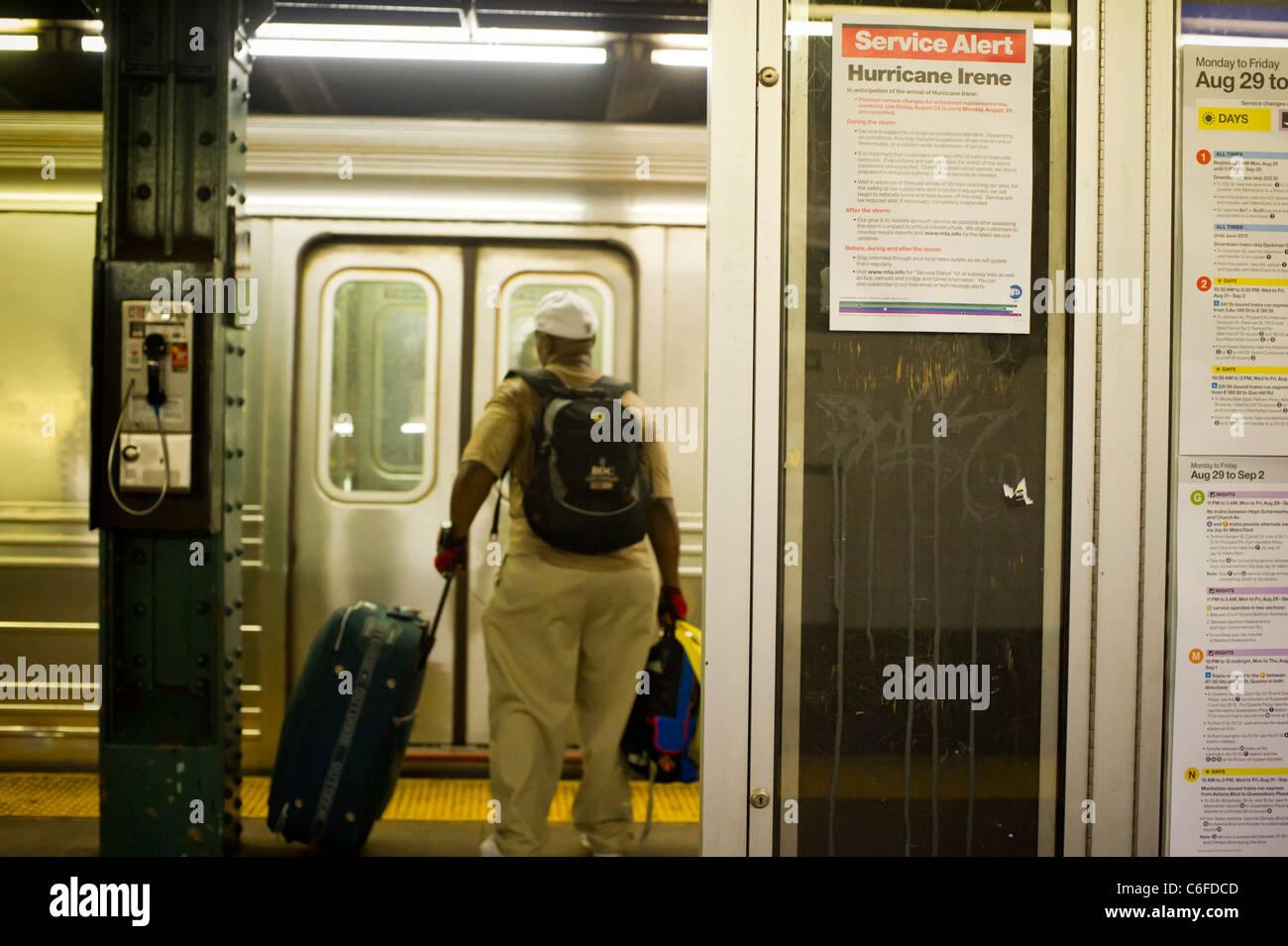 A subway rider with luggage gets on the subway at the West Fourth