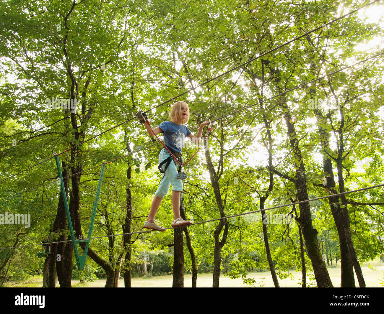 Girl 7 years old walking over steel cable in a climbing adventure park in the Loire valley, France Stock Photo