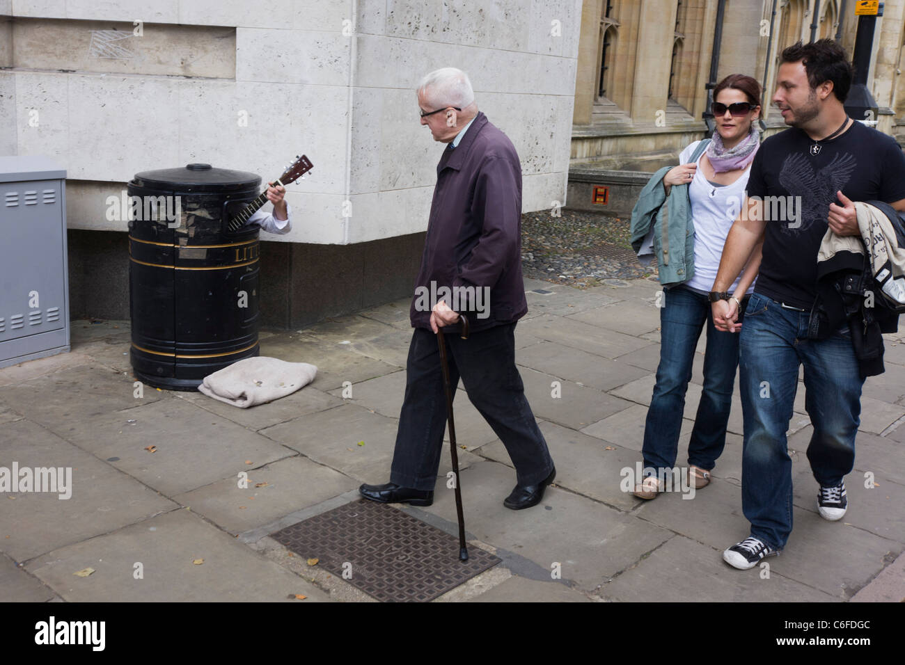 A street busker hides in a litter bin to earn extra cash as passers-by ...