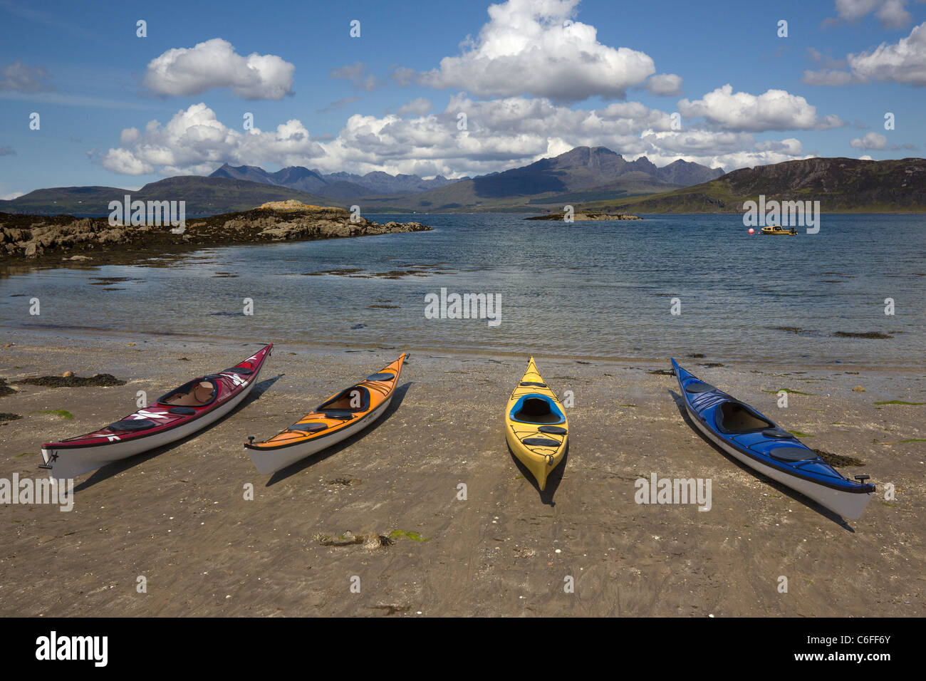 Four sea Kayaks on sandy beach with Loch Eishort and the Cuillin Mountains in the distance, Isle of Skye, Scotland, UK Stock Photo