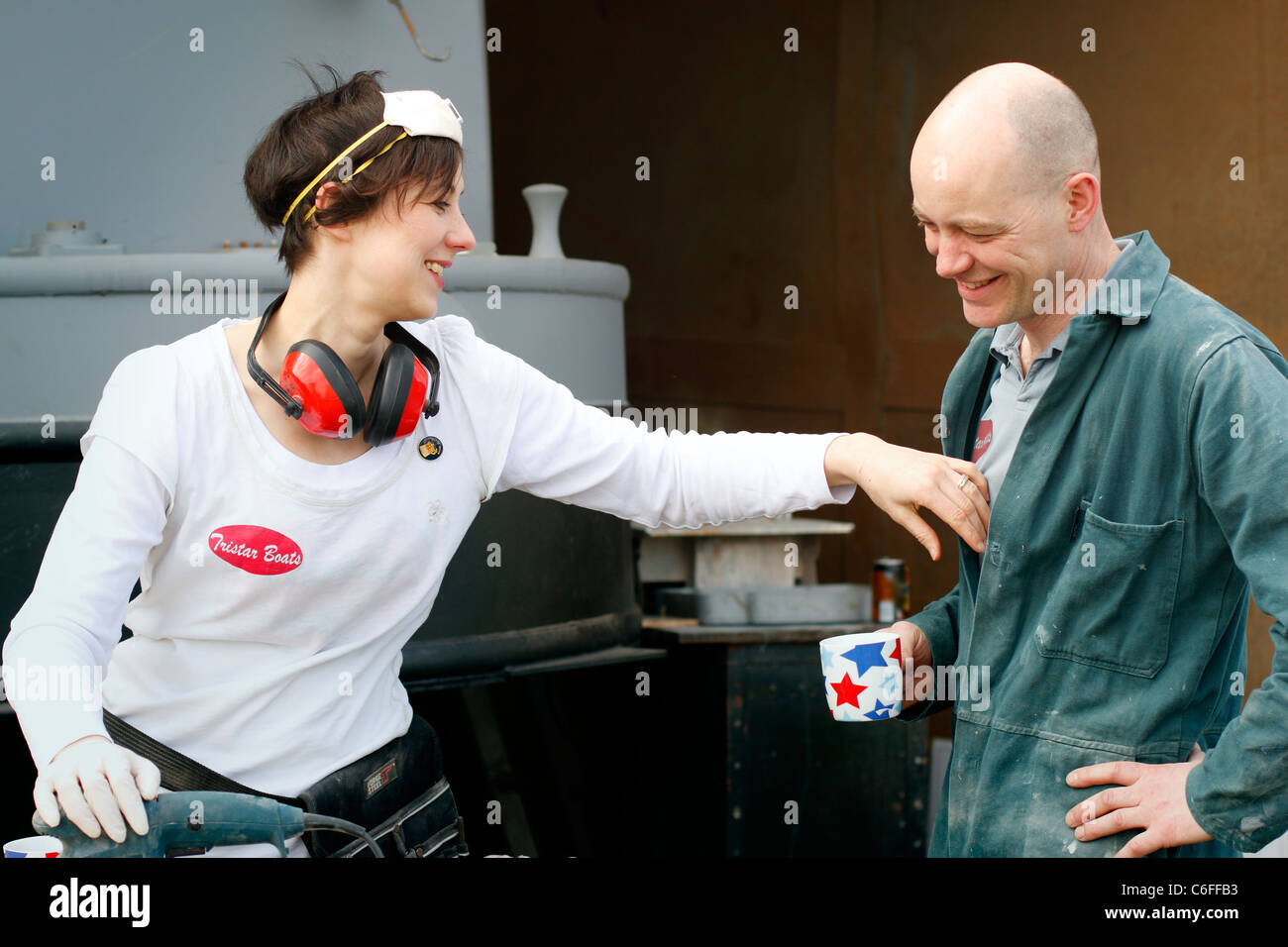 A man and a woman chatting during a break, whilst working on some sanding for the interior of a narrowboat. Wearing PPE. Stock Photo