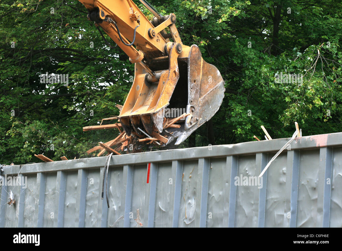 yellow excavator bucket dumping demolition waste into a truck Stock Photo