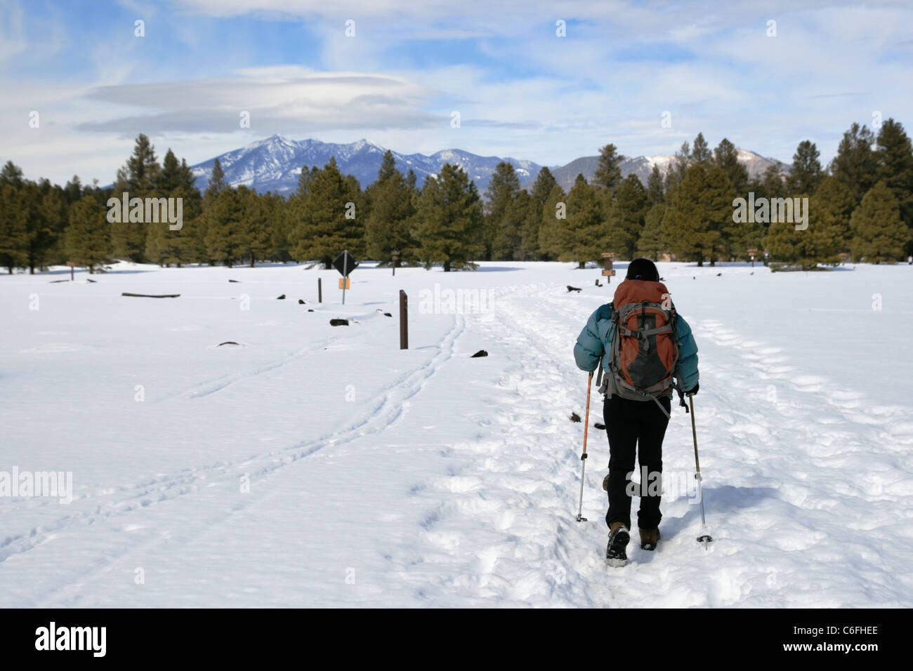 active woman hiking towards distant mountains over the snow Stock Photo