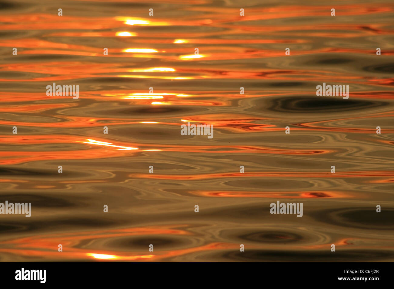 orange sunset reflected on rippling waves in the ocean Stock Photo