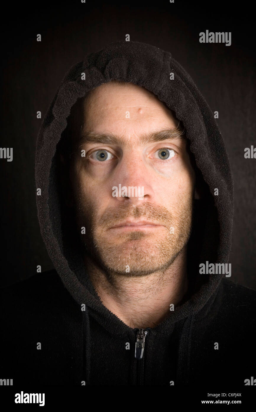 portrait of gritty scruffy hooded man in black Stock Photo
