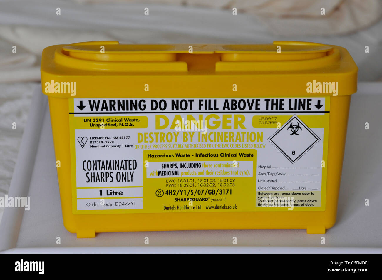 Clinical waste management uk close up yellow plastic box container for correct safe disposal of