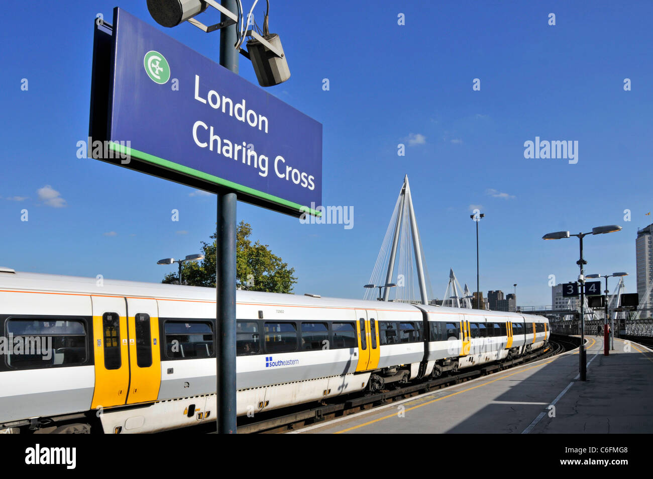 Sign at Charing Cross public transport railway station with South Eastern passenger train carriages at platform on a blue sky day in London England UK Stock Photo