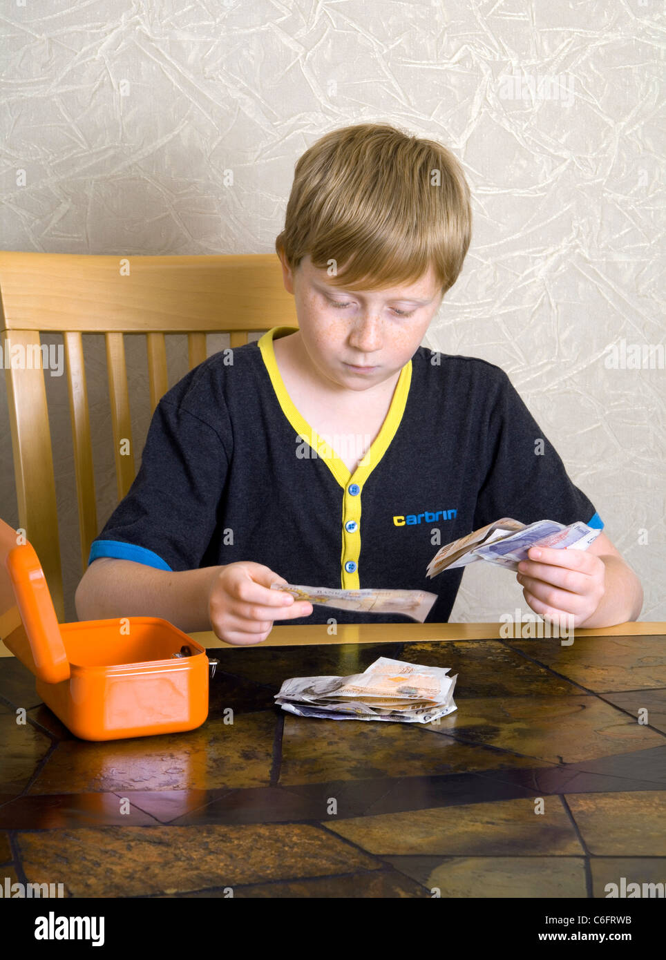 A 12 year old boy counts out British £10 and £20 bank notes Stock Photo