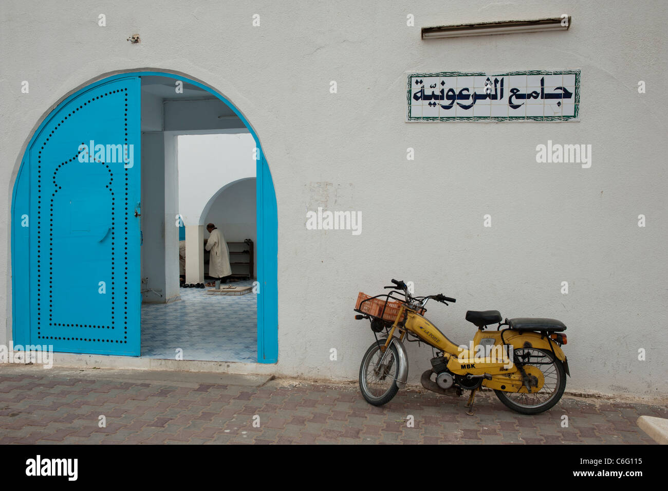 A Tunisian Muslim worshipper removing his shoes before prayer. Guellela Mosque Djerba Tunisia North Africa Stock Photo