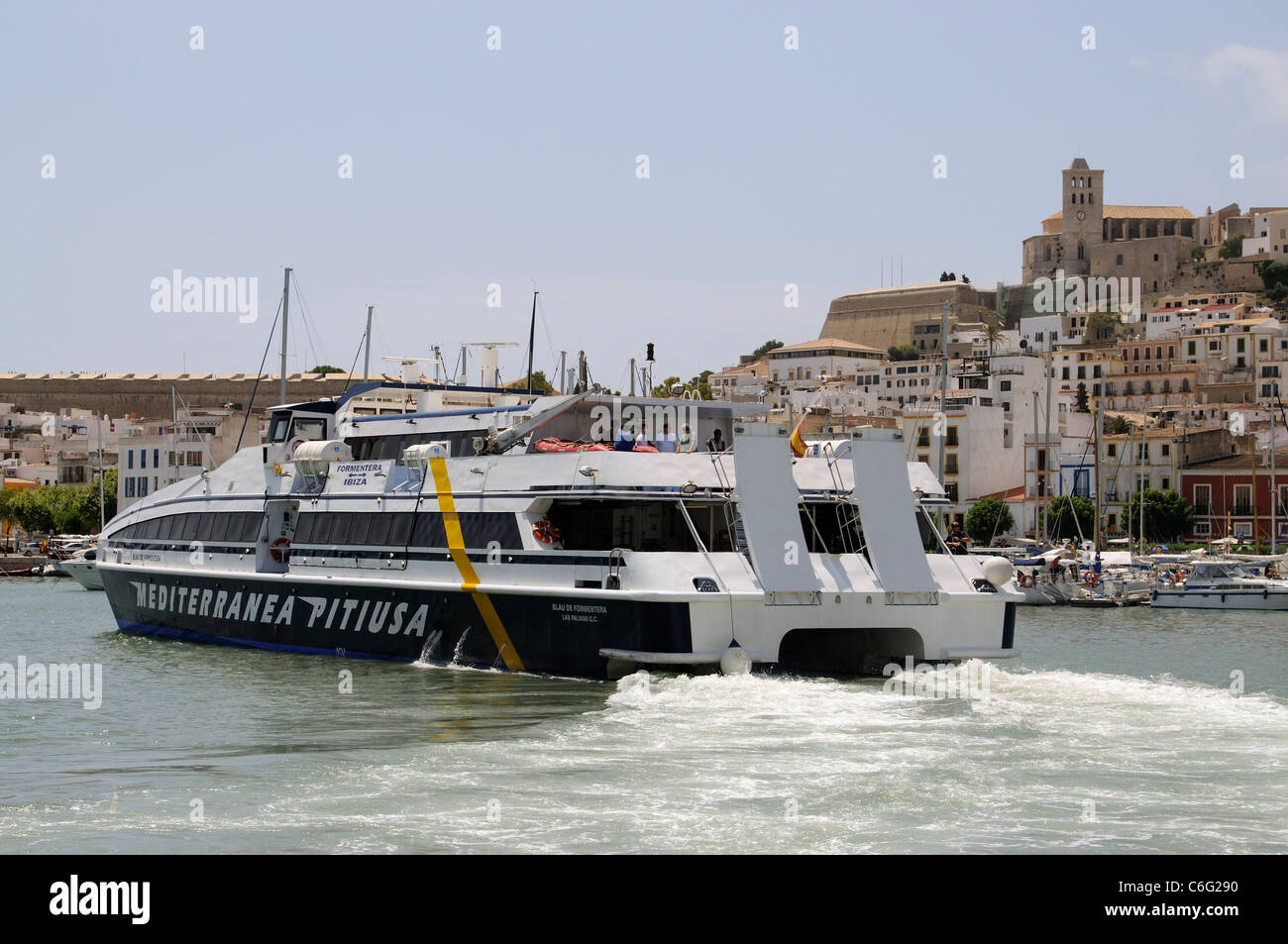 Inter island fast ferry departing the harbour overlooked by the old town of Eivissa on the Spanish Island of Ibiza Stock Photo