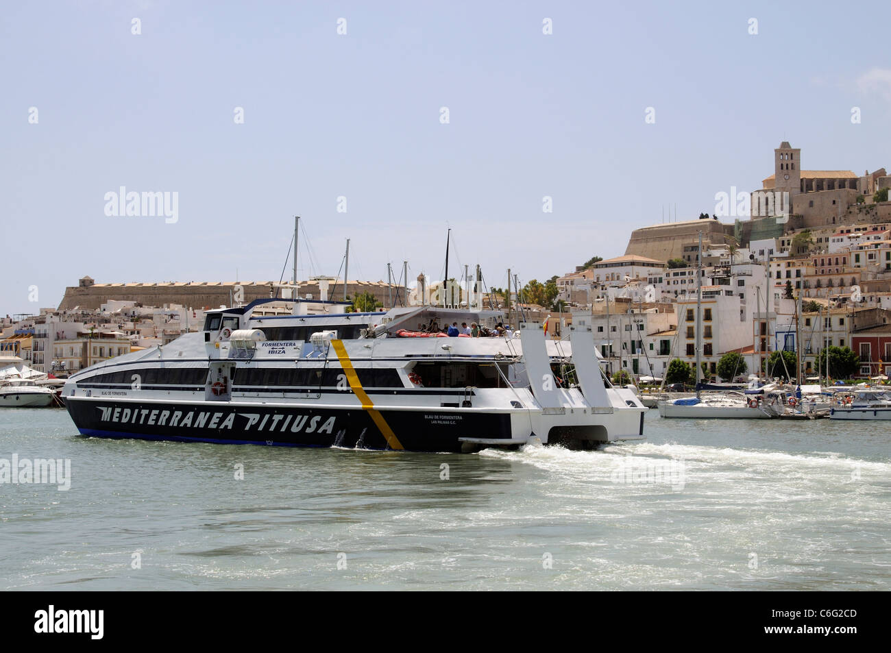 Inter island fast ferry departing the harbour overlooked by the old town of Eivissa on the Spanish Island of Ibiza Stock Photo