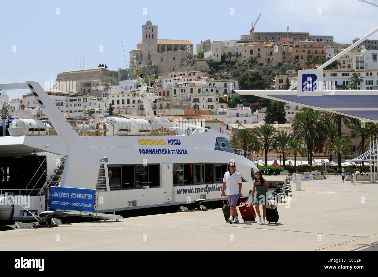 Holidaymakers on the quayside overlooked by the old town of Eivissa on the Spanish Island of Ibiza Stock Photo