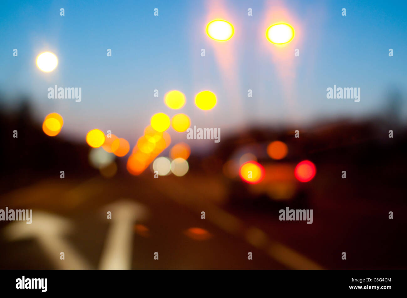 Street lights and car tail lights on a road at dusk Stock Photo