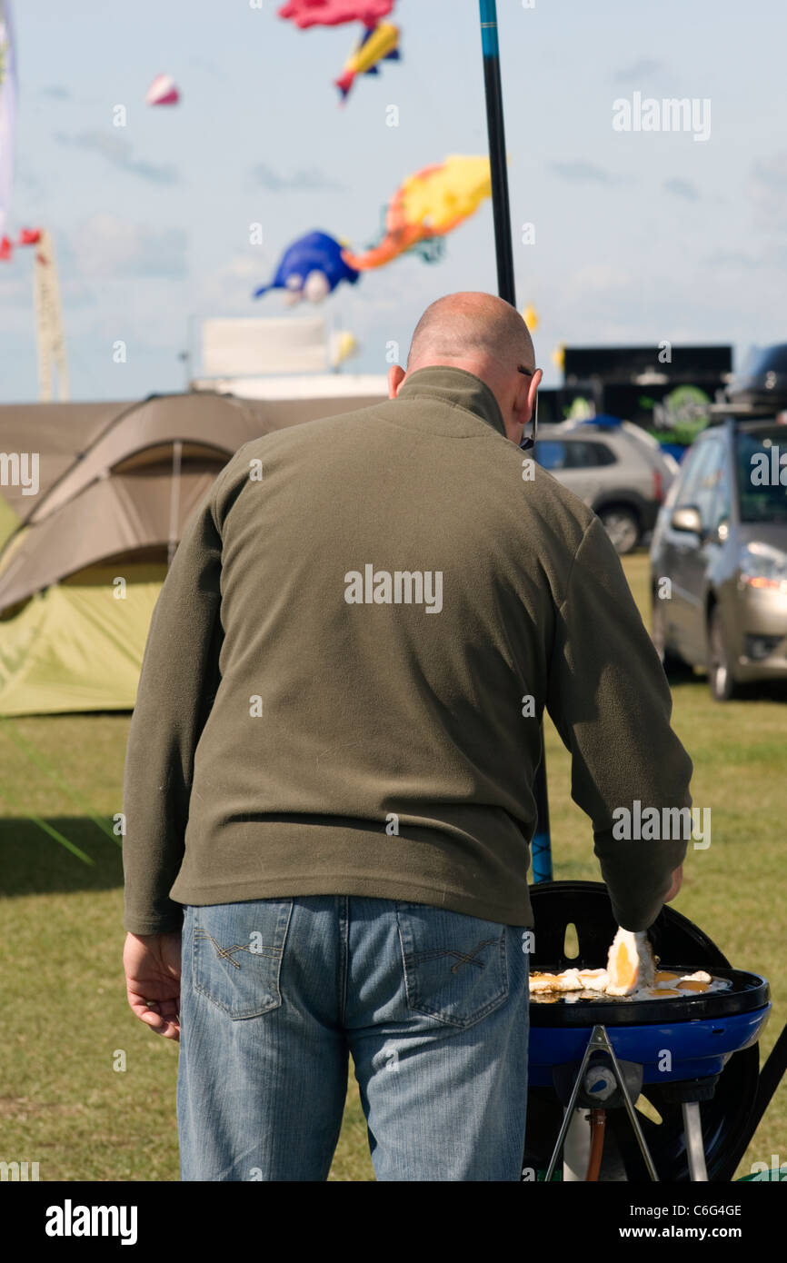 man cooking eggs for breakfast on a barbecue at southsea kite festival