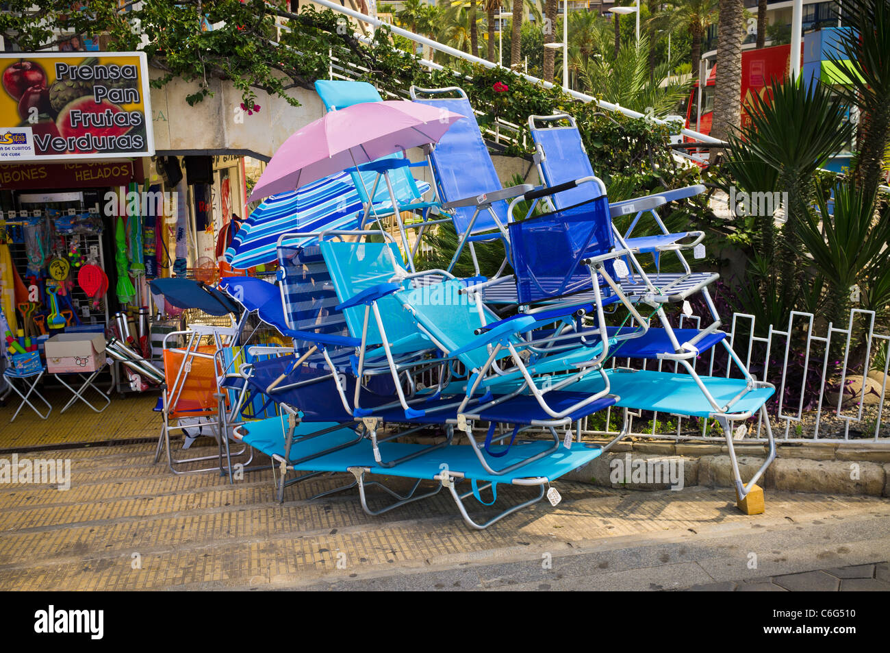 Cheap plastic sun loungers and chairs are piled up outside a shop in Benidorm, Spain. Picture by Brian Hickey Stock Photo