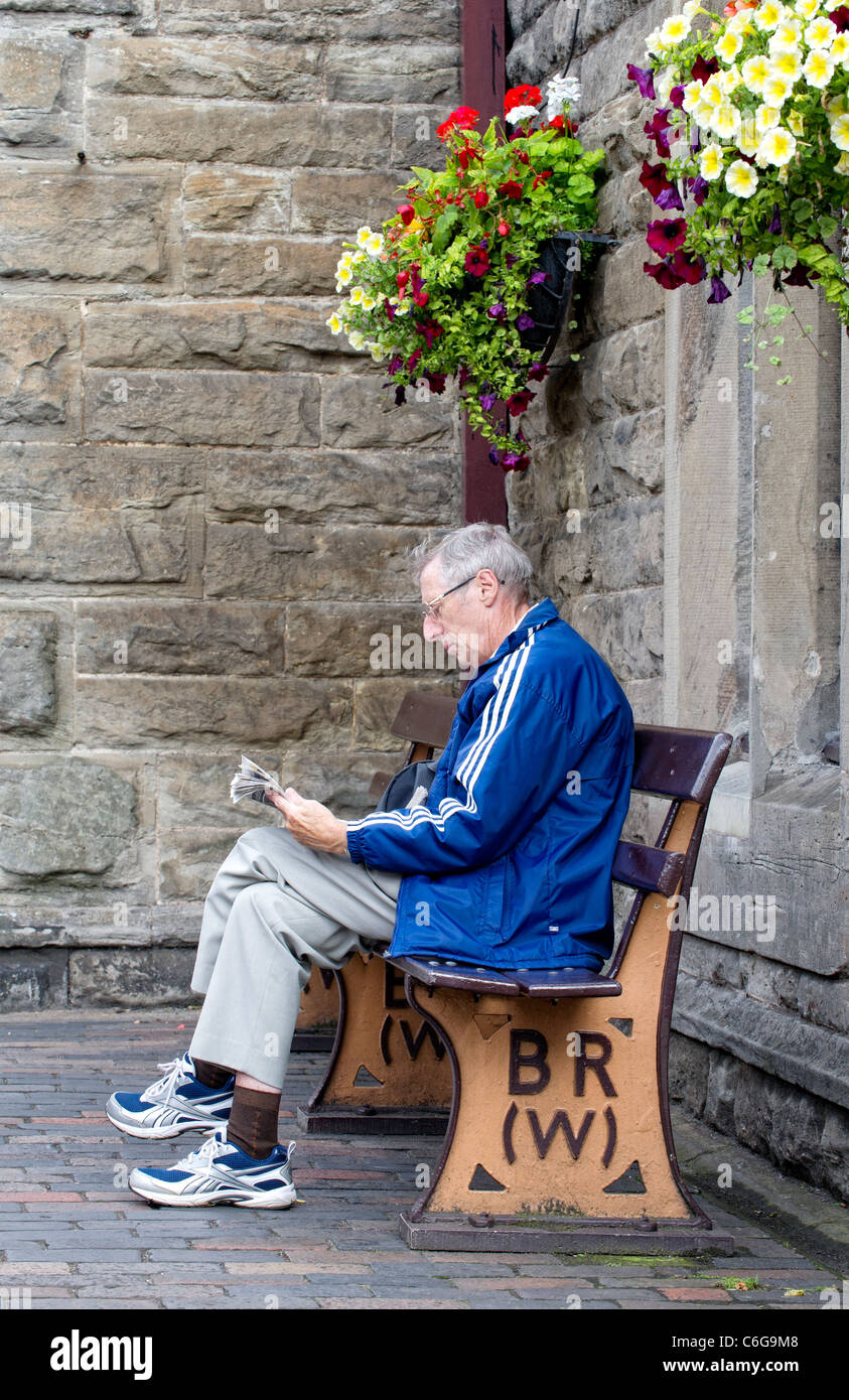 Elderly man sitting on a bench reading Stock Photo - Alamy