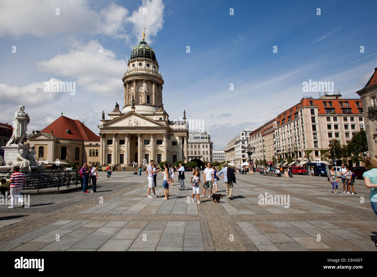 Tourists walking at the Gendarmenmarkt square in Berlin. Franzoesicher dom in the background and Schiller statue at the left Stock Photo